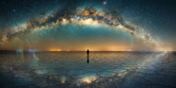 Ilustração cinematográfica de uma silhueta humana solitária observando um céu noturno vasto e repleto de estrelas e galáxias, representando o Paradoxo de Fermi.